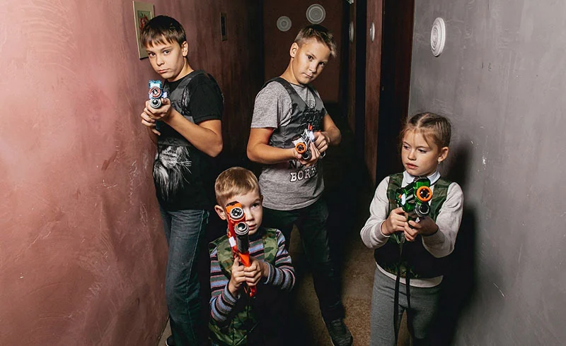 Дети с тагерами в засаде: трое мальчиков и девочка в игровых жилетах